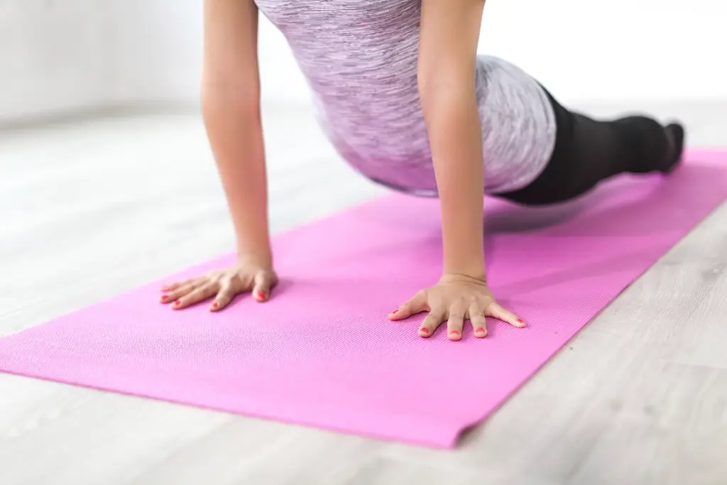 A student pressing into upward-facing dog on a pink yoga mat