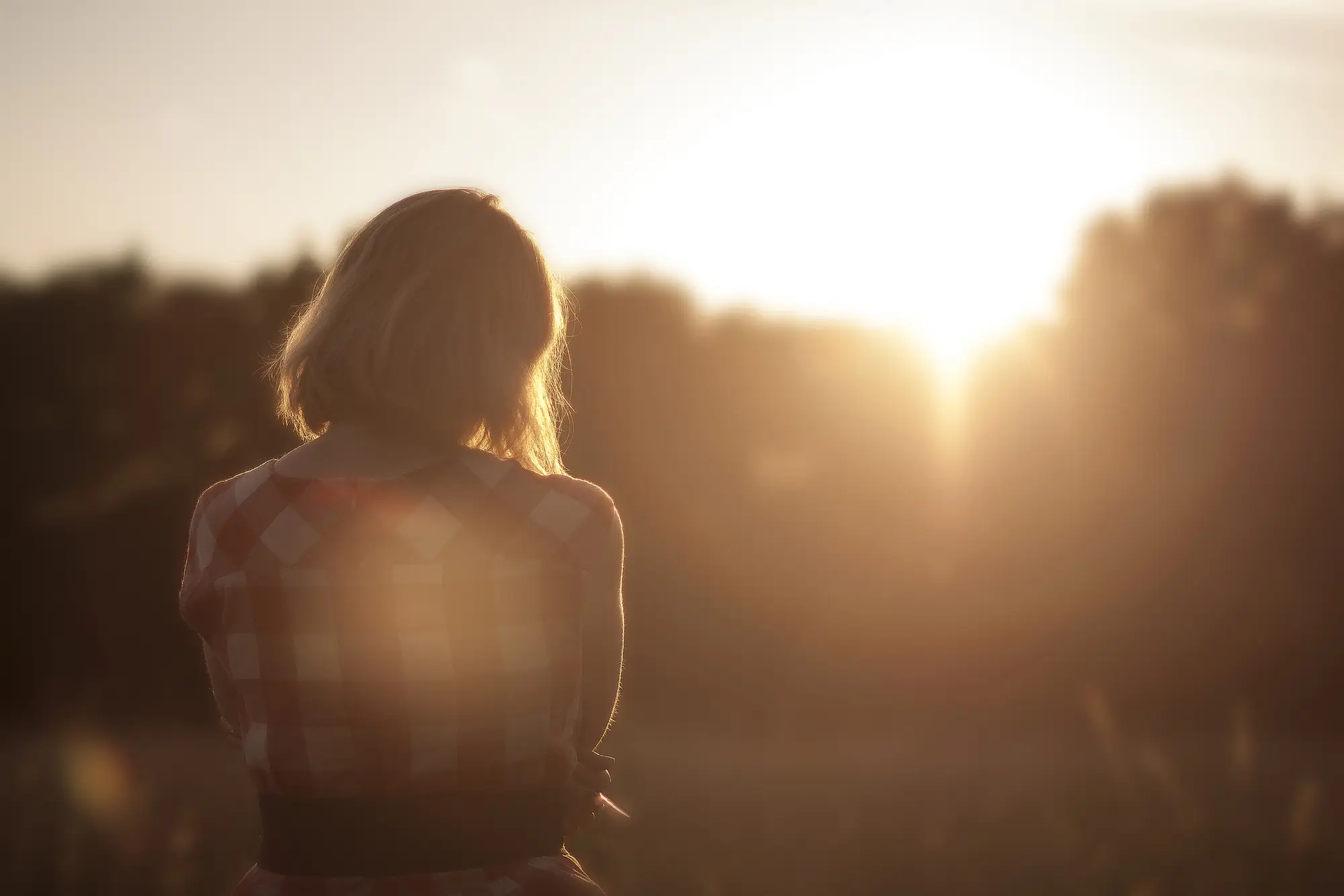 A woman sitting outdoors in warm early morning light